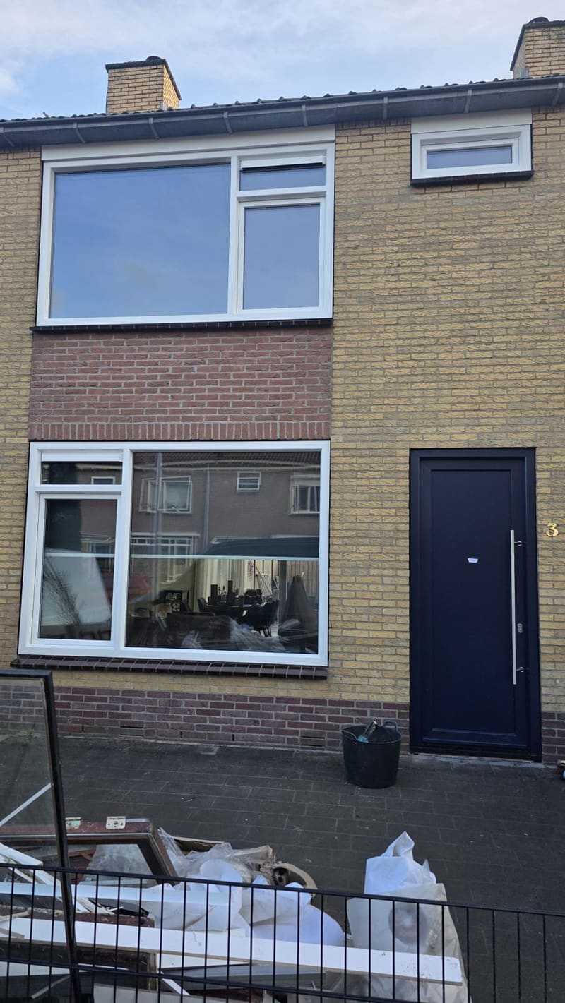 Wit kozijn met grote ruit en antraciet voordeur in een rijtjeswoning